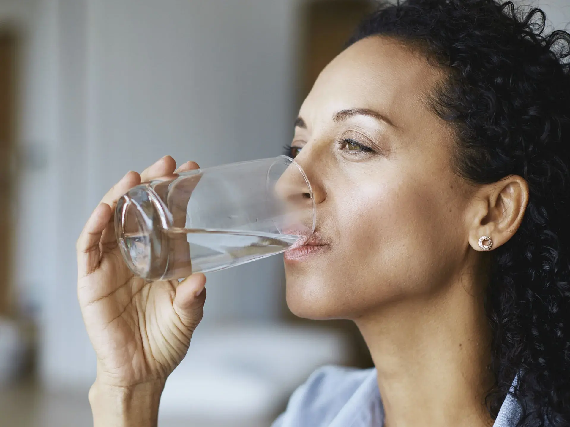 Frau trinkt Wasser aus einem Glas