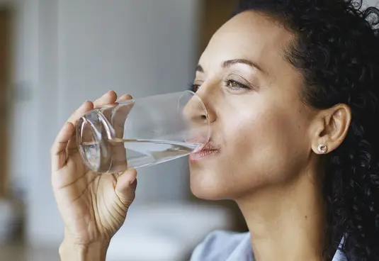 Frau trinkt Wasser aus einem Glas