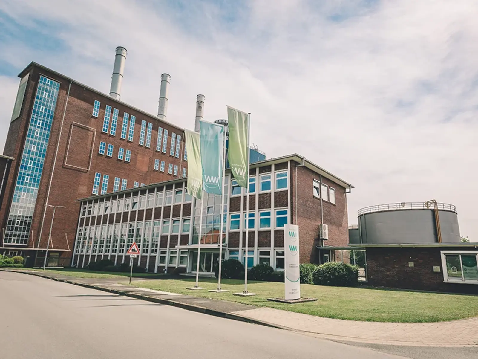 Firmengebäude im Hintergrund mit Fahnen und Mast im Vordergrund 